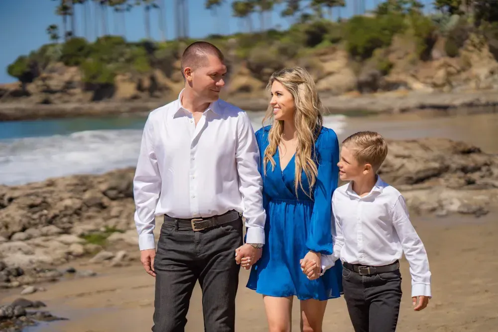 A family is walking on the beach holding hands.