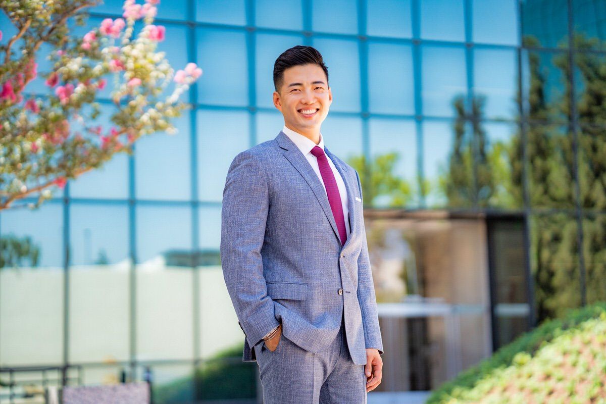 A man in a suit and tie is standing in front of a building in the Noguchi Garden.
