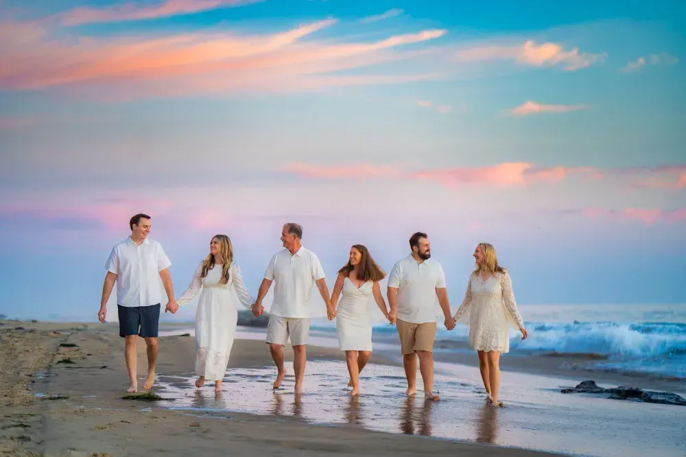 A family walking on the beach holding hands during sunset. 