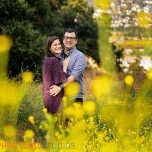 An engaged man and a woman are standing in a field of yellow flowers in Los Angeles