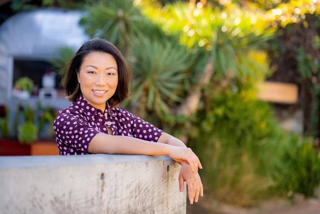 A woman in a purple shirt is leaning on a concrete wall.