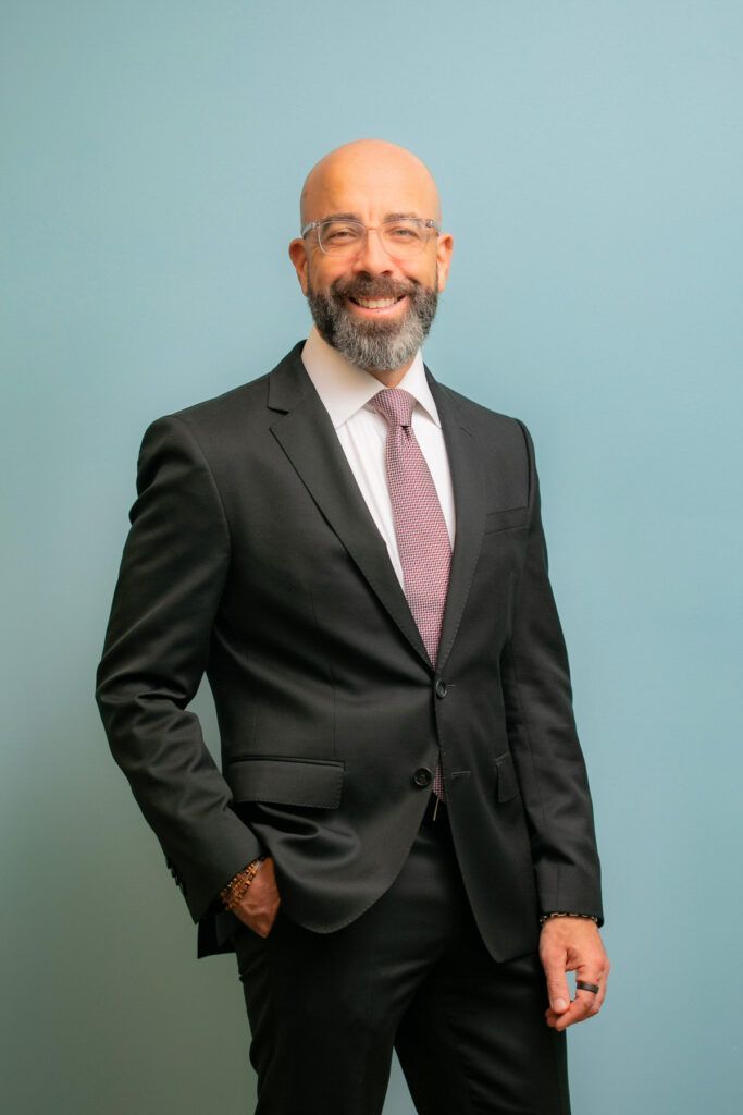 A man in a suit and tie is standing with his hands in his pockets.