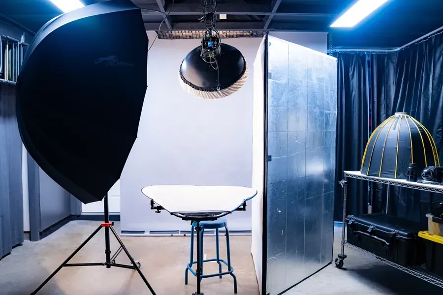 Headshot Studio A photo studio with a table , stools , and lights.