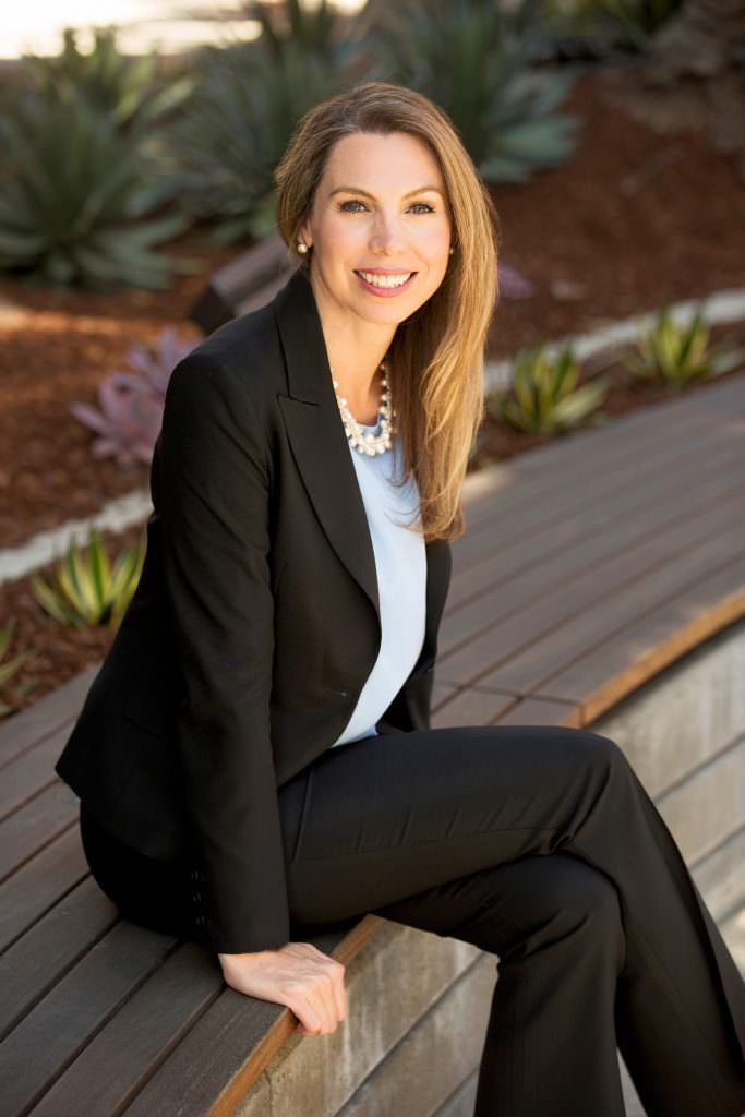A woman in a suit is sitting on a wooden bench.