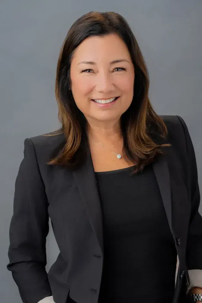 Female Corporate Headshot A woman in a black jacket and black shirt is smiling for the camera.