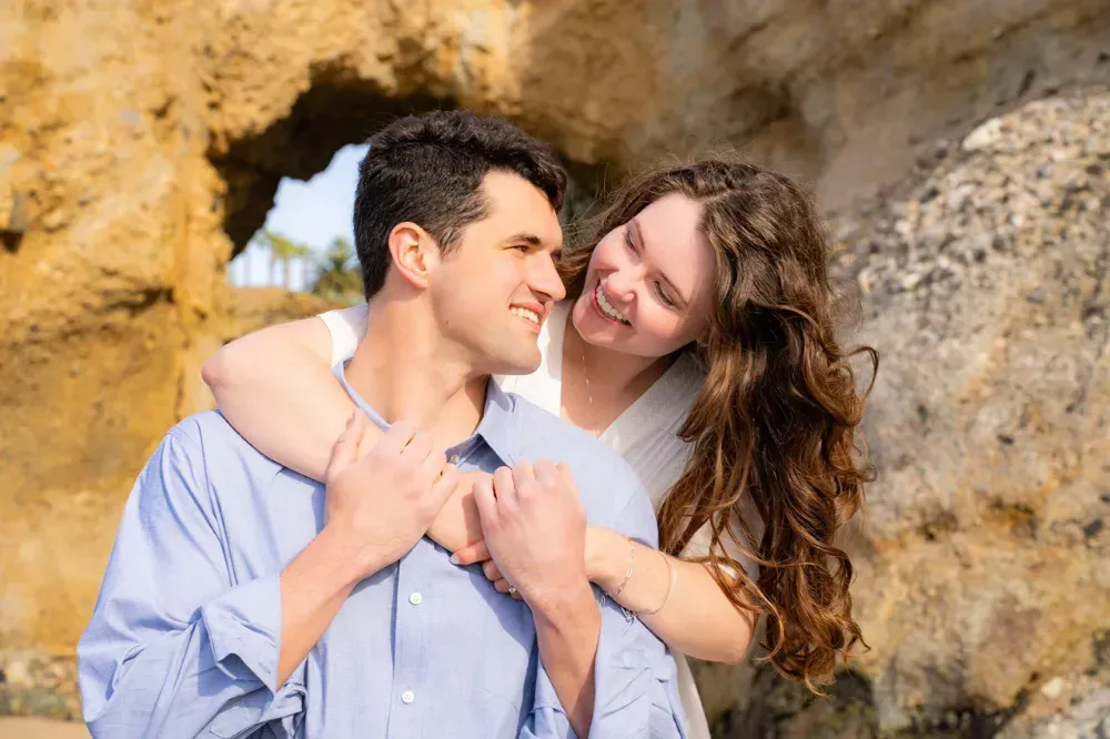 A man and a woman are hugging each other on the beach.