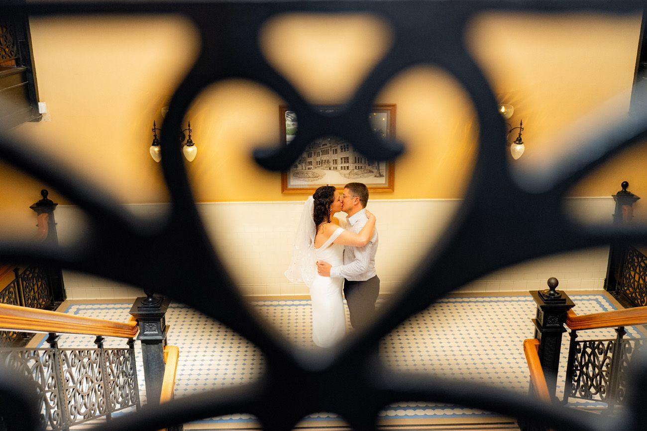 The Old Historic courthosue in Santa Ana A bride and groom kissing through a heart-shaped fence at the historic courthouse in Orange County.