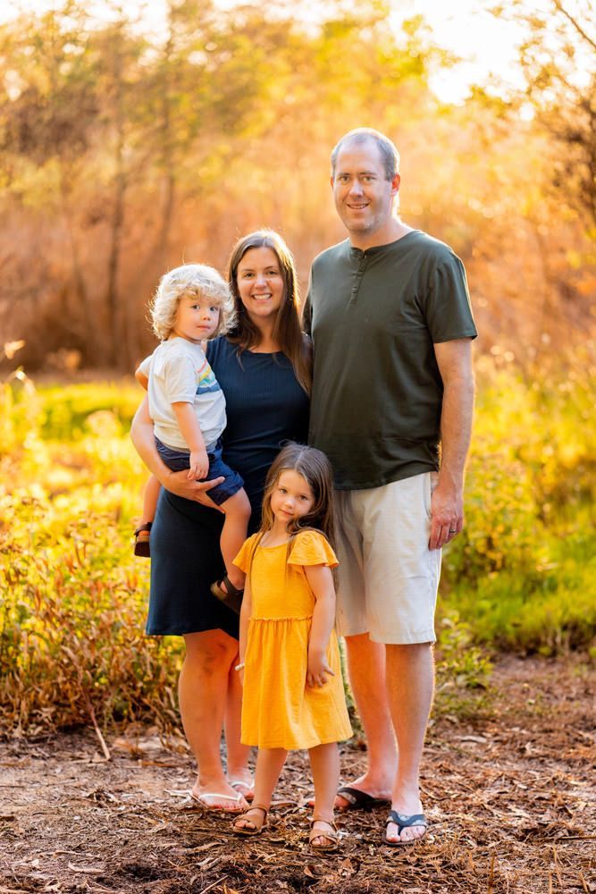 A family is posing for a picture in the woods.