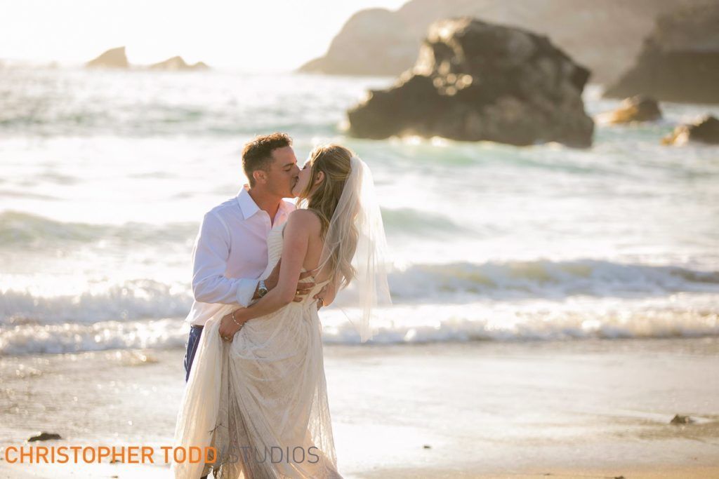 A bride and groom are kissing on the beach on Catalina Island