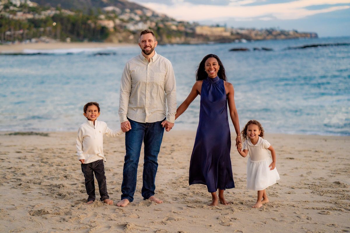 Family Portrait Photography A family is standing on a beach holding hands.