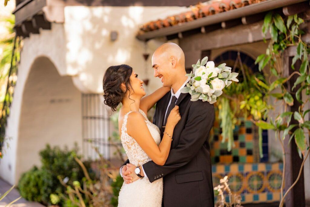 A bride and groom are posing for a picture in front of the Laguna Beach City Hall.