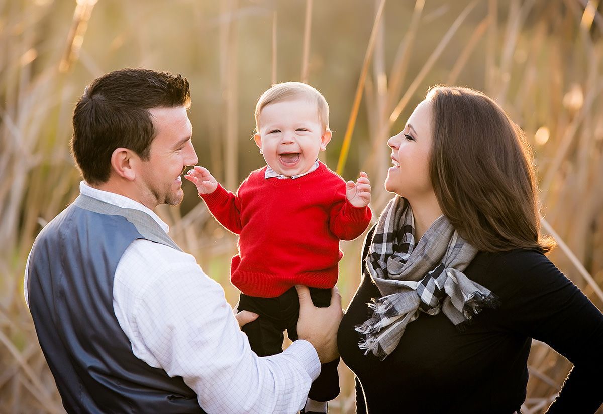 Outdoor Fun Family Portrait A man and a woman are holding a baby in a field.