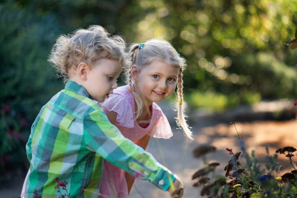 A boy and a girl are looking at flowers in Huntington Central Park Garden in candid photo.