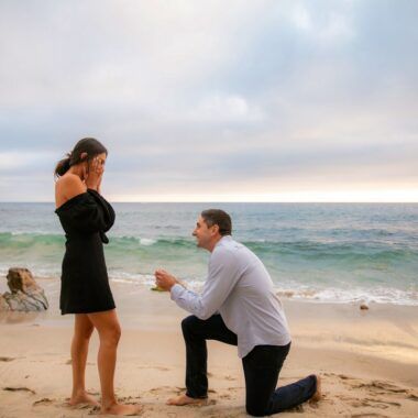 A man is proposing to a woman on Little Corona Beach in Orange County.
