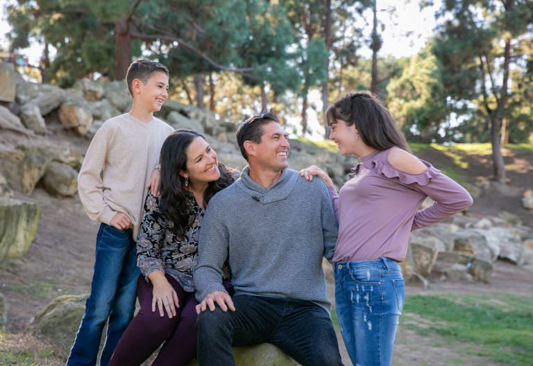 Tewinkle Park Costa Mesa A family is sitting on a rock in a park.