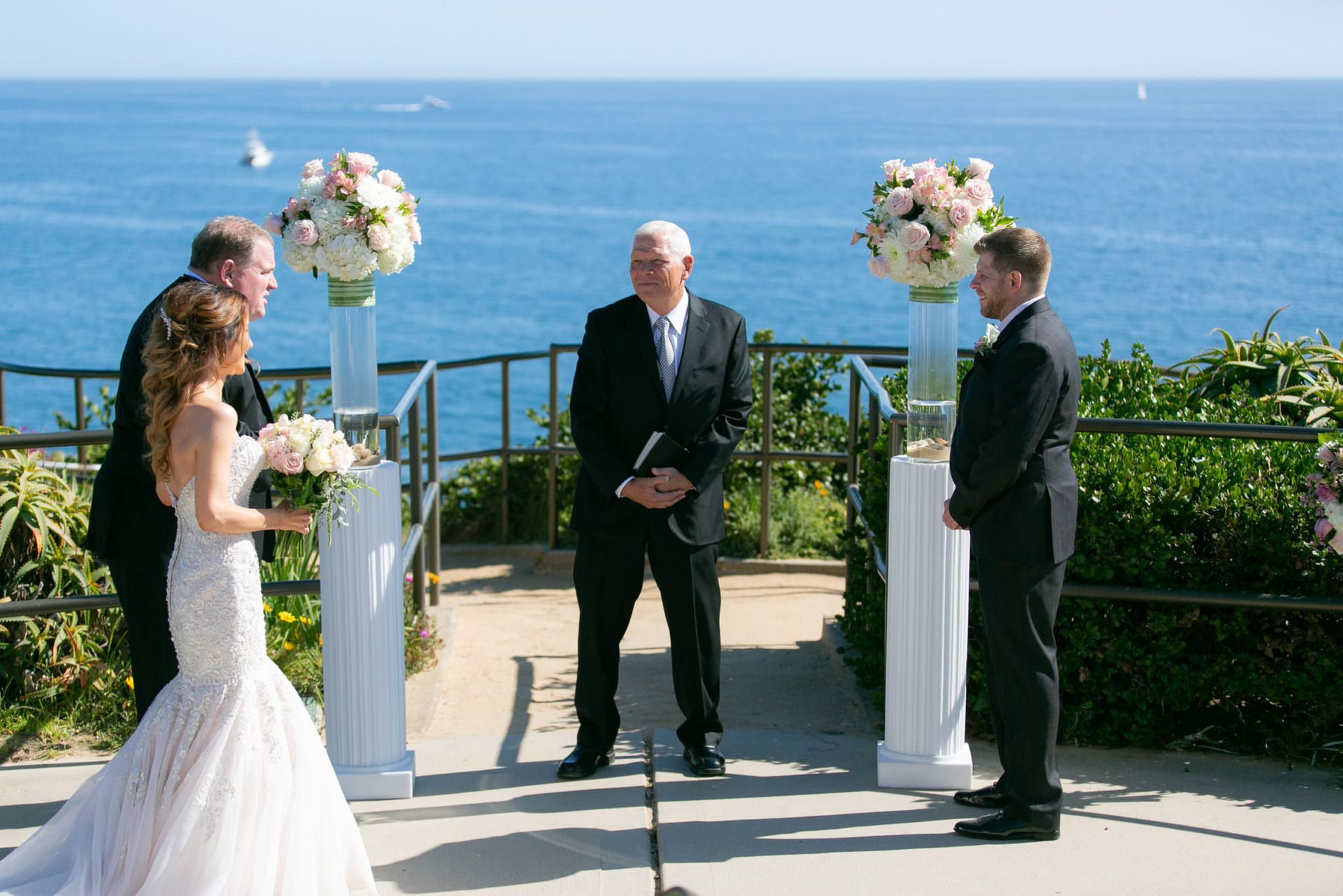 A wedding dress is hanging on a balcony overlooking the ocean.