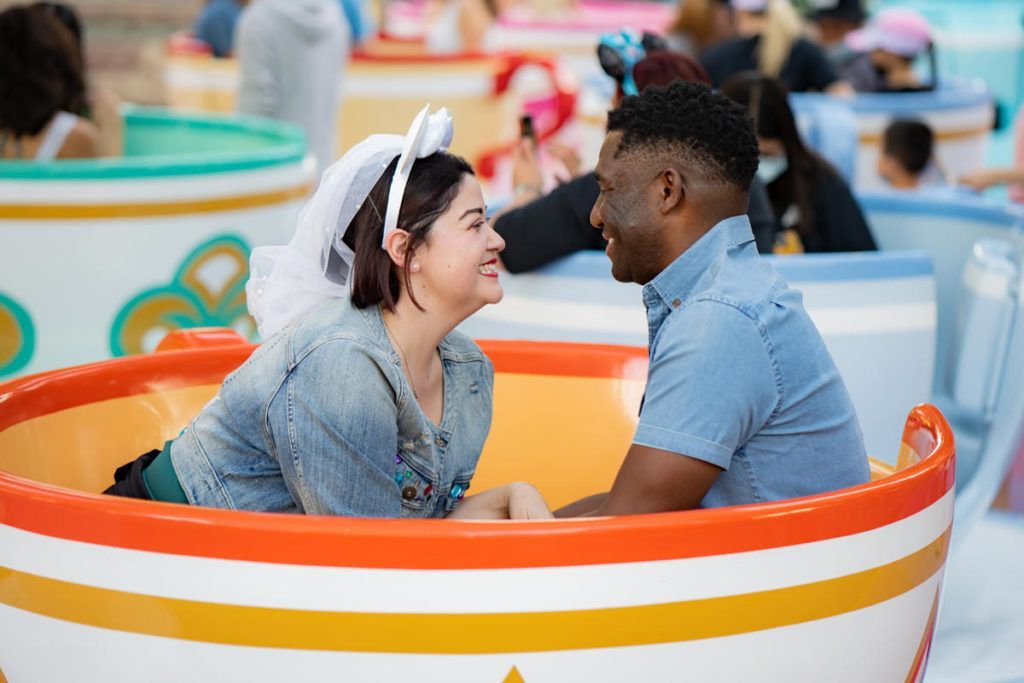 A man and a woman are sitting in a tea cup and looking at each other.