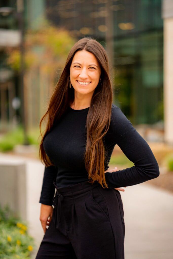 A woman in a black shirt and black pants is posing for a picture.