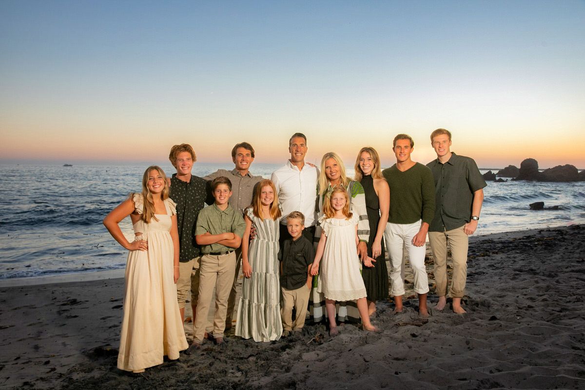 Large Group Family Beach Portrait A large family is posing for a picture on the beach at sunset.