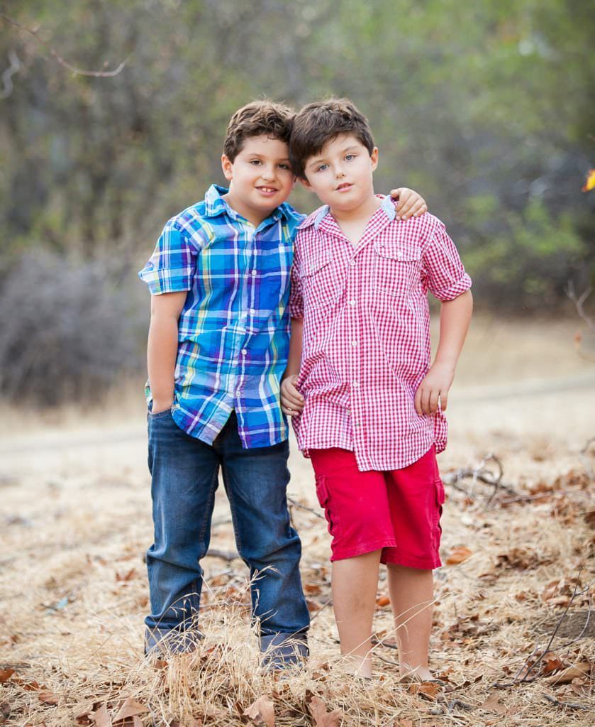 Two young boys are standing next to each other in a field in a local park in Orange California.
