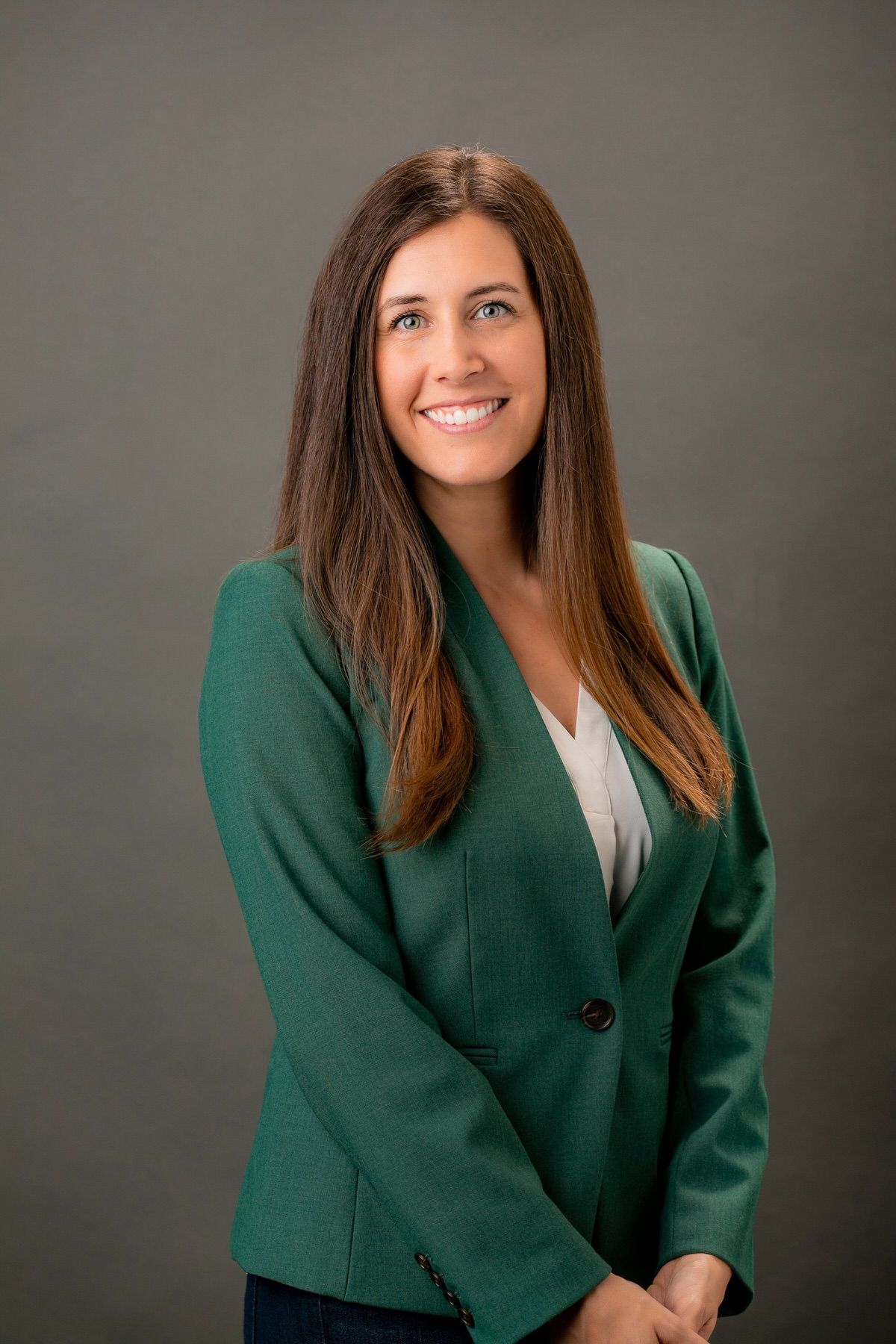 Woman in a green jacket poses for a headshot in a studio