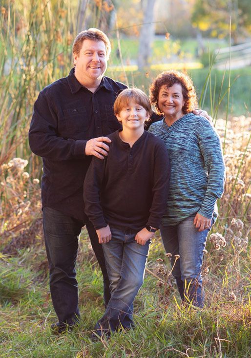 A man , woman and child are posing for a picture in a field.