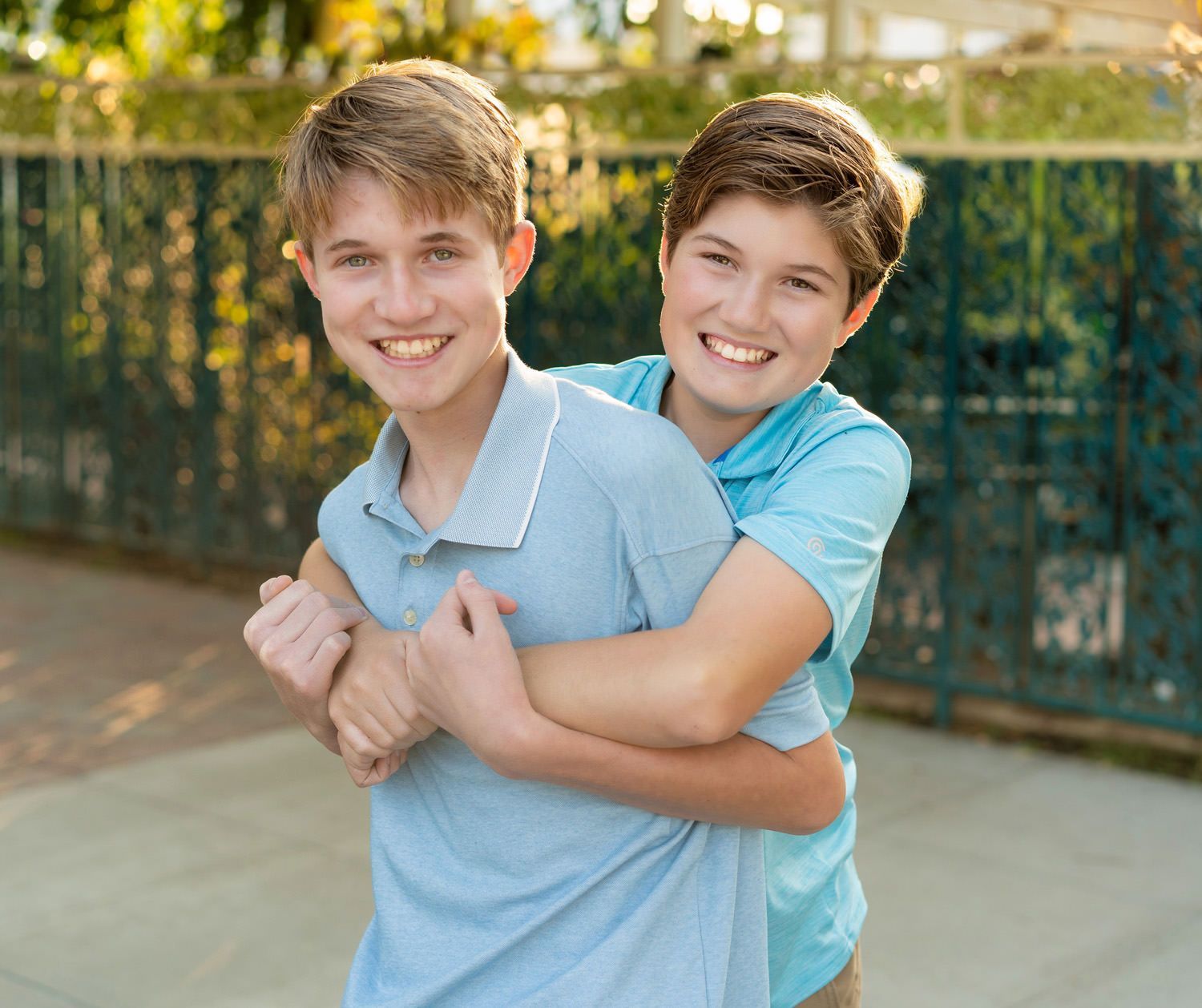 Seal Beach family photo session Two teenage brothers are hugging each other on a sidewalk on Main Street in Seal Beach.