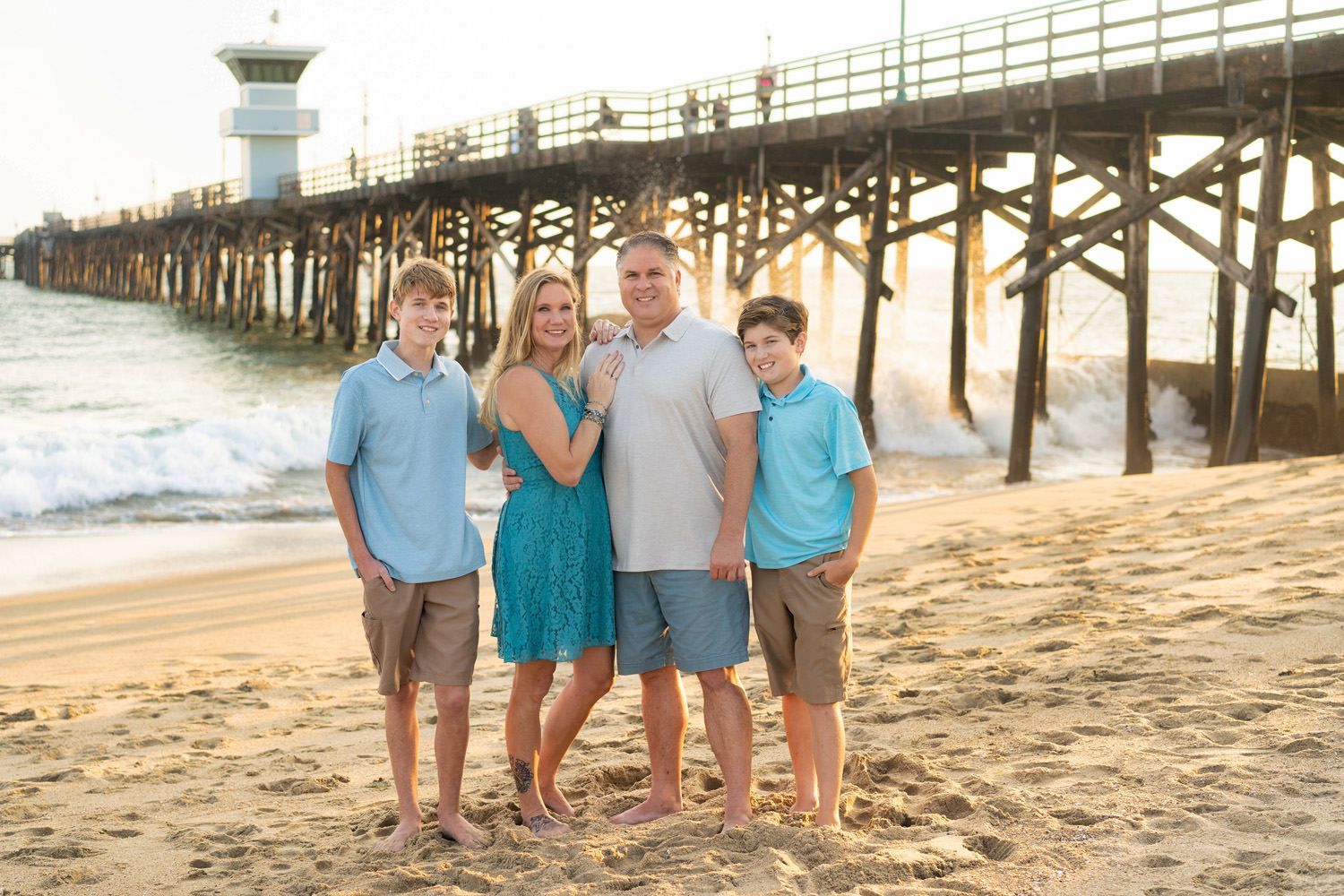 Seal Beach pier family photos A family is posing for a picture on the beach in front of the Seal Beach pier.