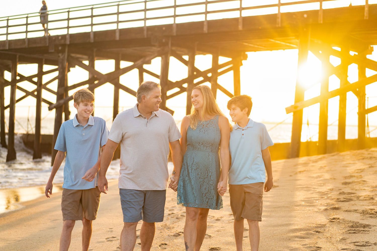 Seal Beach Pier Family Portrait A family is walking on the beach near a pier at sunset in Seal Beach.