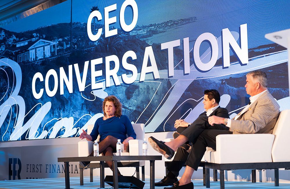 Corporate Event Photographer Dana Point A group of people are sitting on a stage in front of a sign that says ceo conversation.