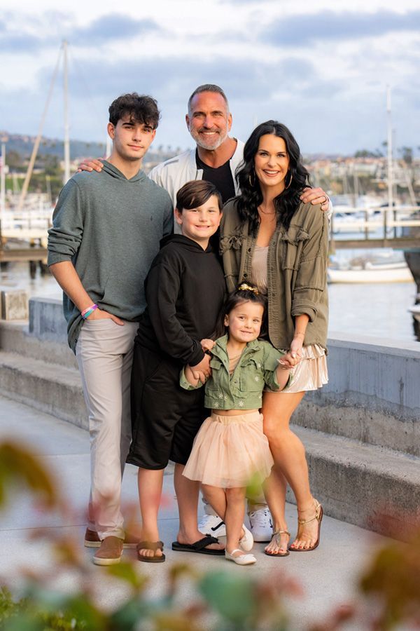 A family is posing for a picture in front of a marina.