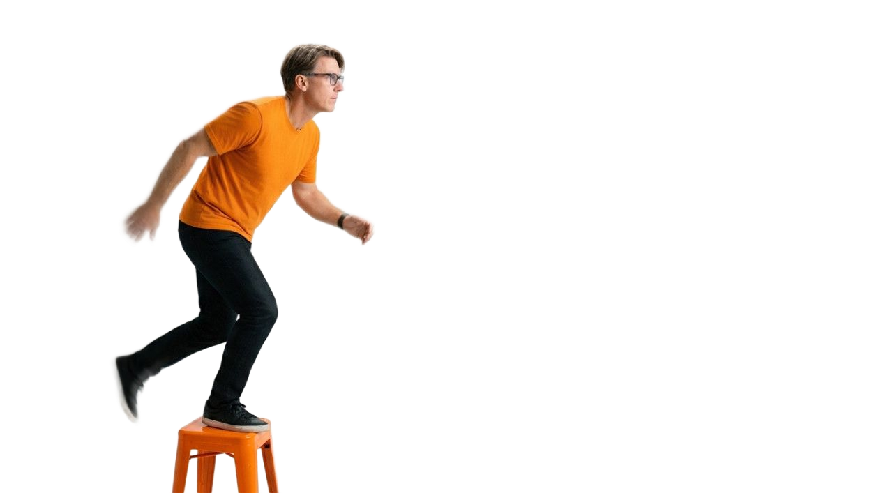 convention photographer southern california A person in an orange t-shirt and black pants steps off an orange stool against a white background.