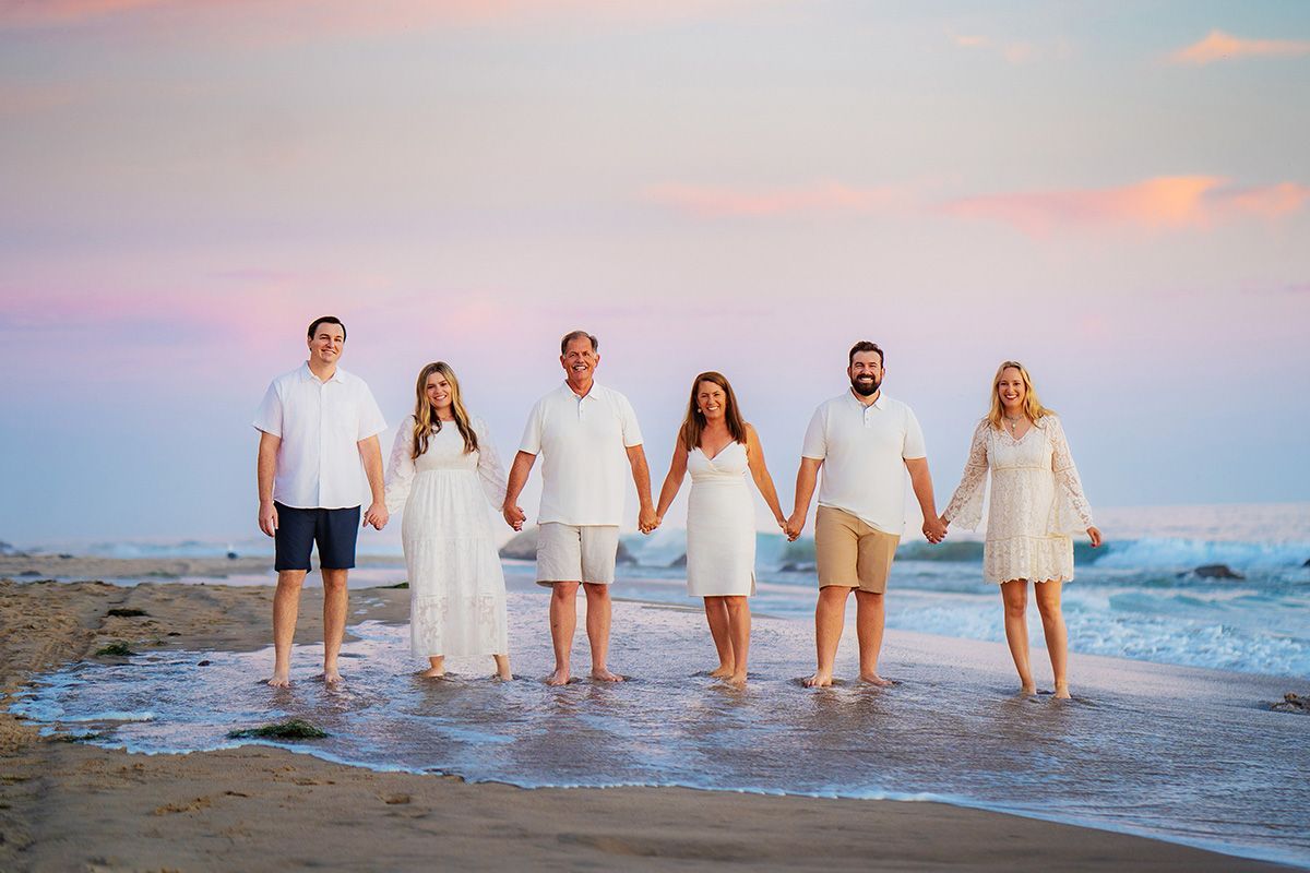 A group of people are standing on a beach holding hands in san clemente beach