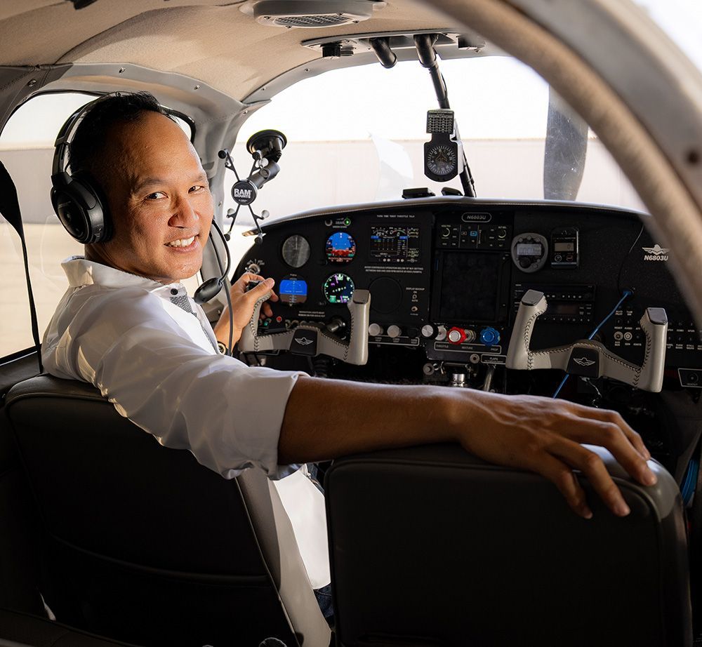 A man wearing headphones is sitting in the cockpit of an airplane.