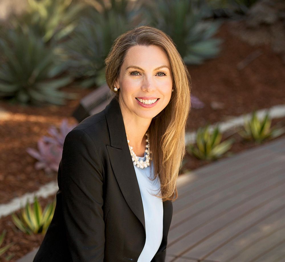 A woman in a black jacket and blue shirt is smiling for the camera.