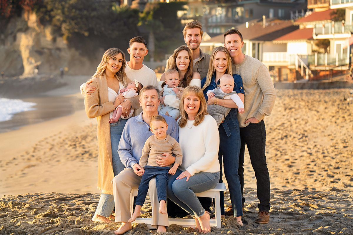 A large family is posing for a picture on the beach.
