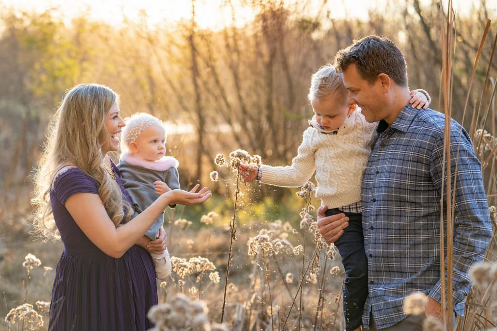 A family is standing in a field of tall grass in Huntington Beach Central Park. 