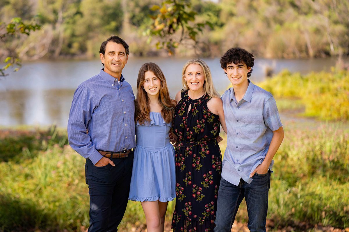 A family is posing for a picture in front of a lake.