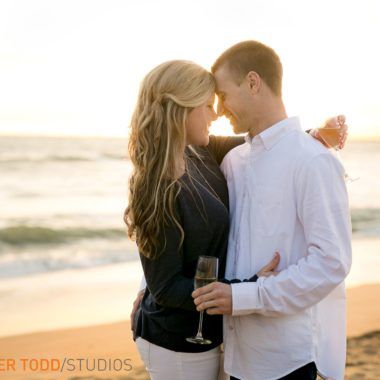 A man holding a glass of wine stands next to a woman on the beach in Orange County