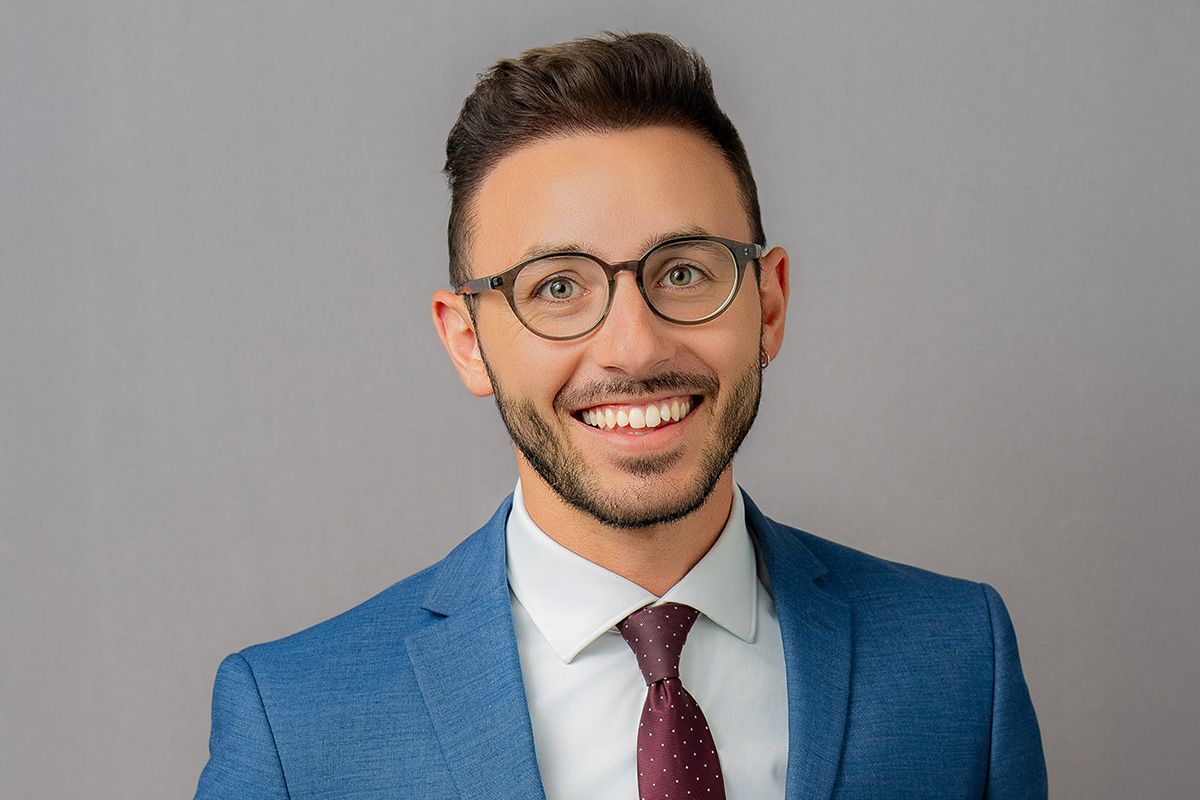 A headshot of a man in a suit and tie is smiling for the camera.
