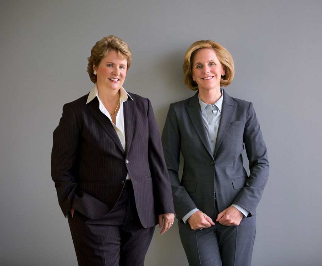 Two women in business suits are standing next to each other