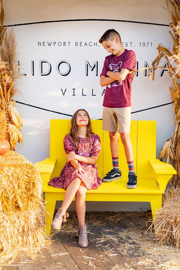 A boy and a girl are sitting on a yellow bench.
