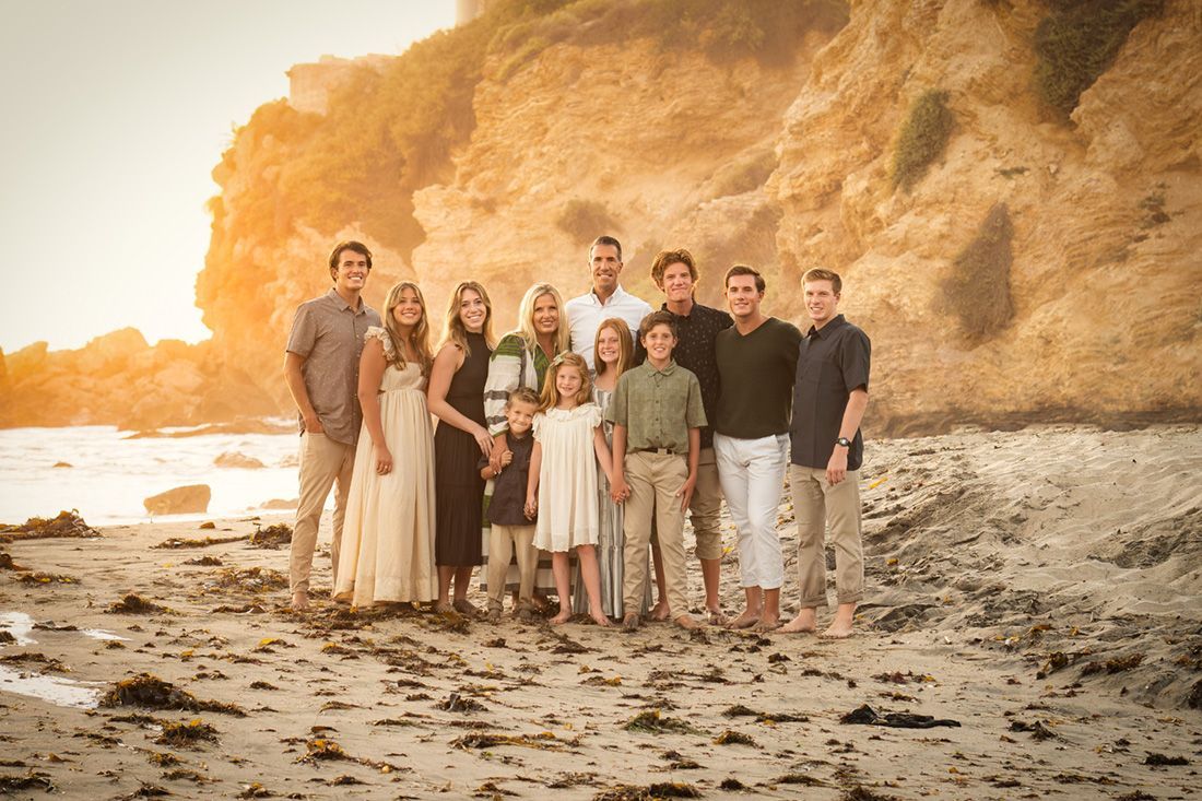 A large family is posing for a picture on the beach.