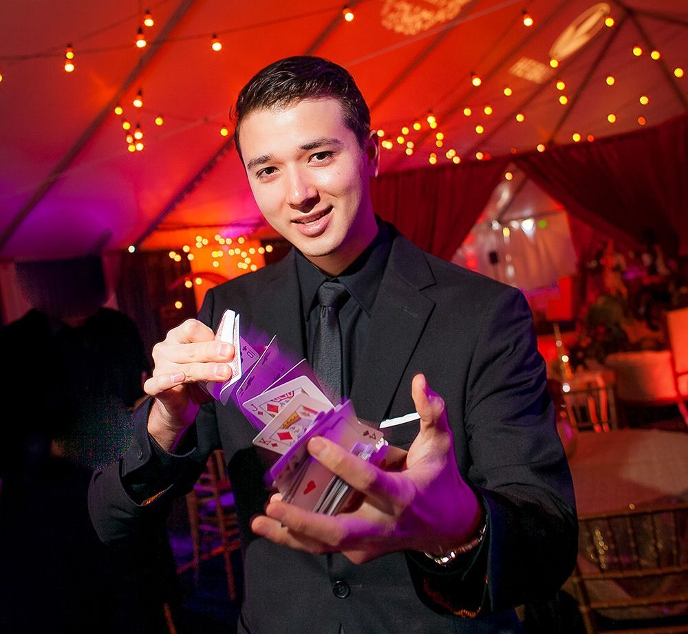 A man in a suit and tie is holding a stack of playing cards