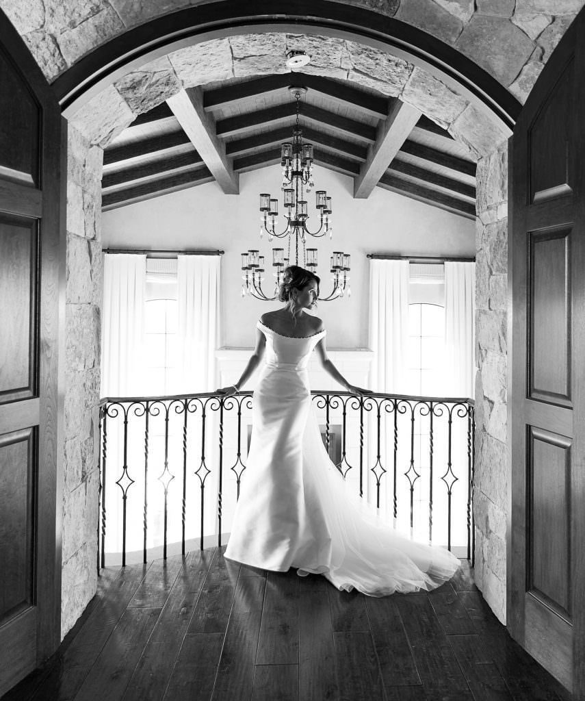 A black and white photo of a bride standing on a balcony