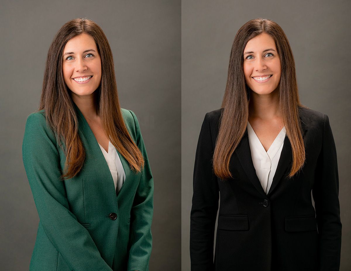 Realtor Headshots Irvine Ca. A smiling person in a blue suit and red tie sitting at a wooden table with a laptop in a brightly lit office.