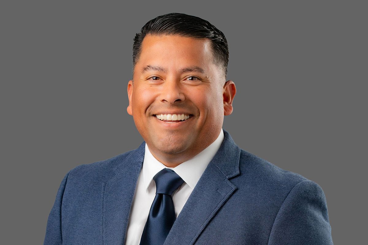 Dana Point Professional Headshot A man in a suit and tie is smiling for the camera in front of gray background
