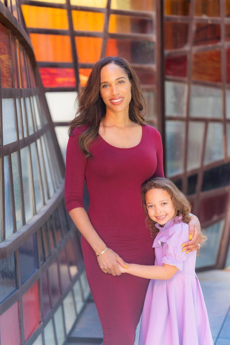 A woman and a little girl are holding hands in front of a stained glass window at Noguchi gardens