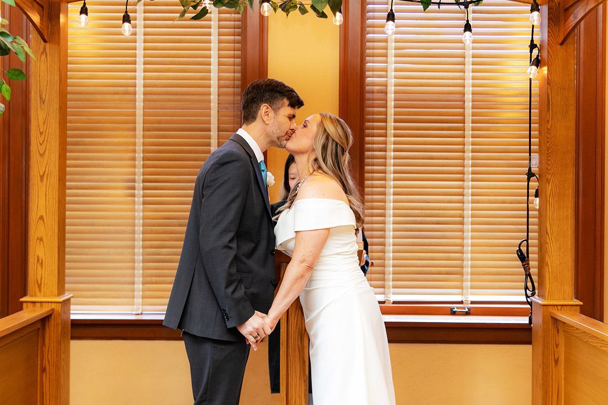 A bride and groom are kissing in a civil wedding ceremony at the Old Orange County Courthouse in Santa Ana.