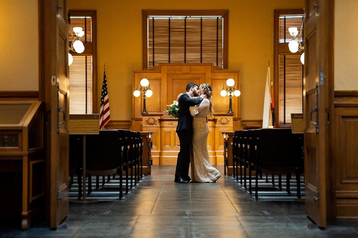 Orange County Courthouse Wedding Photographer A bride and groom are kissing in a courtroom.